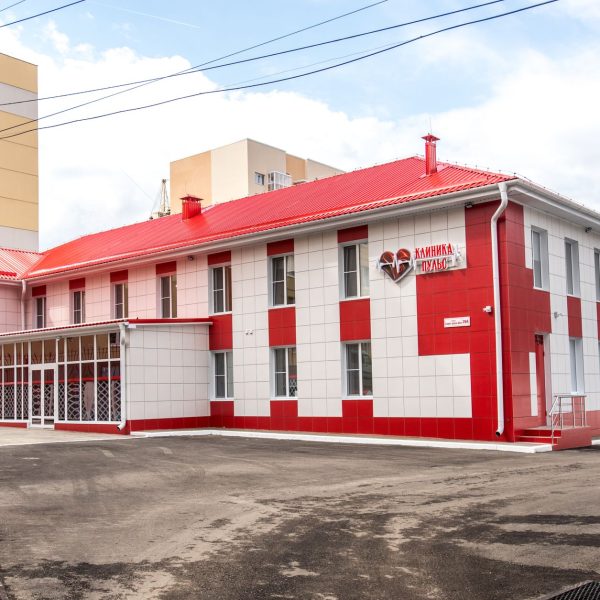 Fachada de uma clínica moderna com estrutura nas cores vermelha e branca.