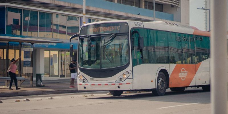 Ônibus urbano parado em um ponto enquanto passageiros embarcam.