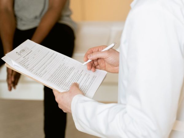 Profissional de saúde analisa um formulário durante atendimento em uma clínica.