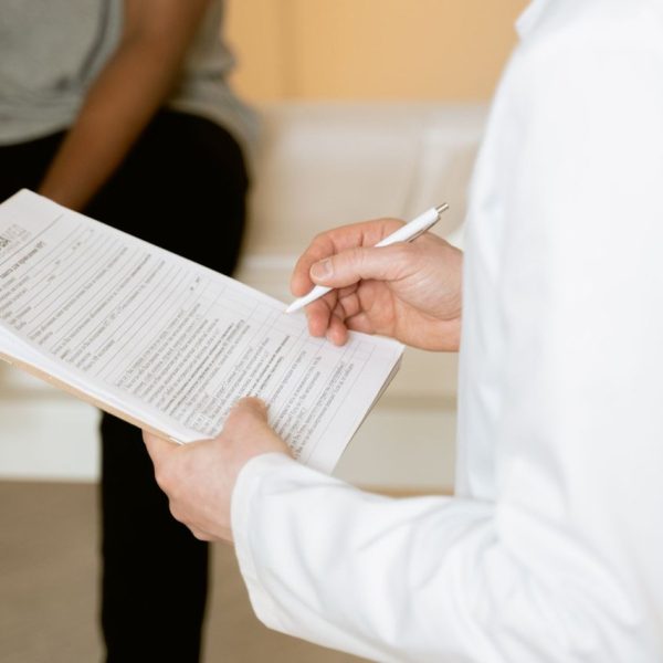 Profissional de saúde analisa um formulário durante atendimento em uma clínica.