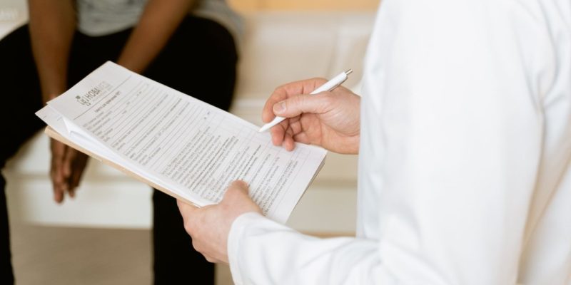 Profissional de saúde analisa um formulário durante atendimento em uma clínica.